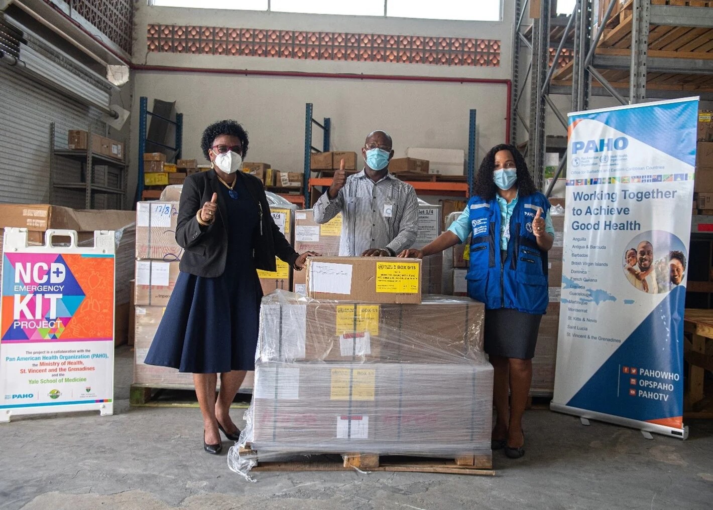 paho-ncd-kits-stvincent three people wearing masks posing in a distribution centre