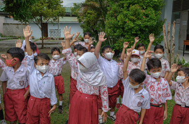 Elementary school students raising their hands.