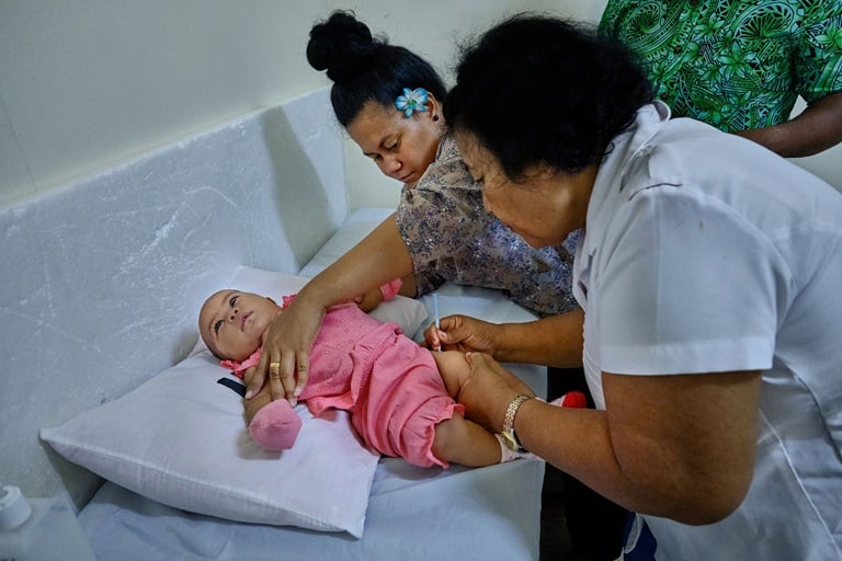 Immunization A baby is vaccinated by a nurse while her mother holds the baby's arms.